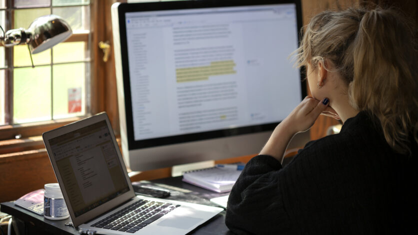 Kvinna sammanfatta resultat och skriver på dator och stor bildskärm